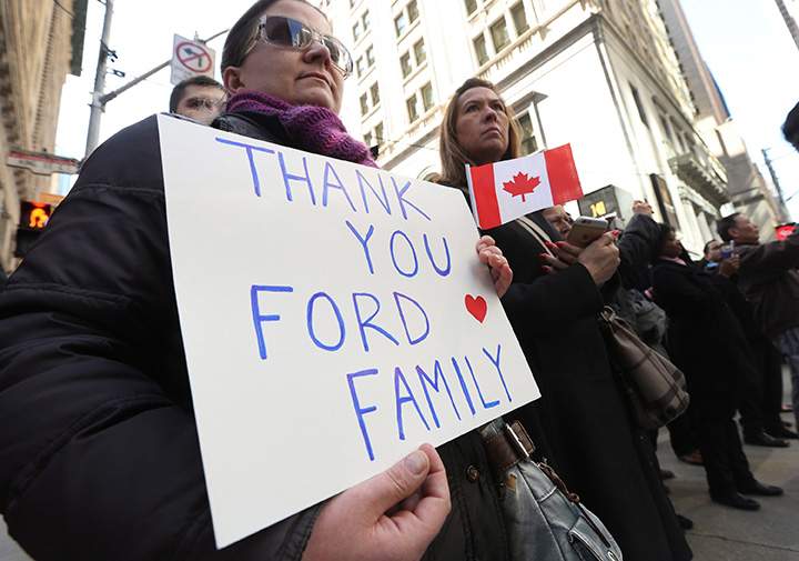 A woman holds a sign of support as the funeral procession for former mayor Rob Ford makes its way from City Hall to St. James Cathedral in Toronto on Wednesday, March 30, 2016.