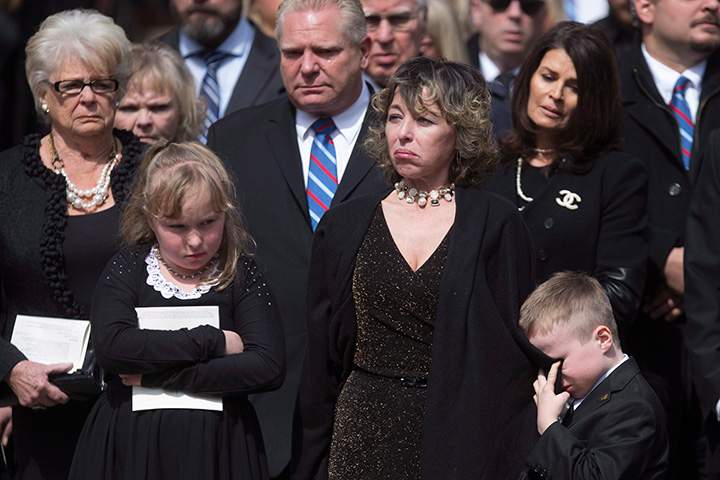 Rob Ford’s son Dougie cries into his mother Renata’s coat as he stands with his sister Stephanie grandmother Diane and uncle Doug as they watch Rob Ford’s casket being placed in the hearse following a service at Toronto’s St. James Cathedral, on Wednesday, March 30, 2016.
