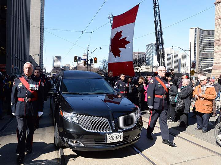An honour guard escorts the hearse carrying the casket of former Toronto mayor Rob Ford from city hall during his funeral procession to St. James Cathedral in Toronto on Wednesday, March 30, 2016.