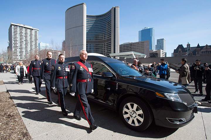 An honour guard escorts the hearse carrying the casket of former Toronto mayor Rob Ford from city hall during his funeral procession to St. James Cathedral in Toronto on Wednesday, March 30, 2016.