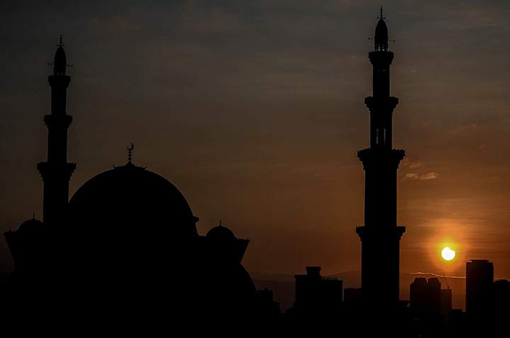 A general view shows a partial solar eclipse behind the Wilayah mosque in Kuala Lumpur on March 9, 2016.