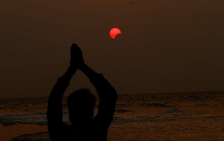 An Indian fisherman prays to a partial solar eclipse seen in the sky over Bay of Bengal in Konark, 60 kilometers from eastern Indian city Bhubaneswar, Wednesday, March 9, 2016.