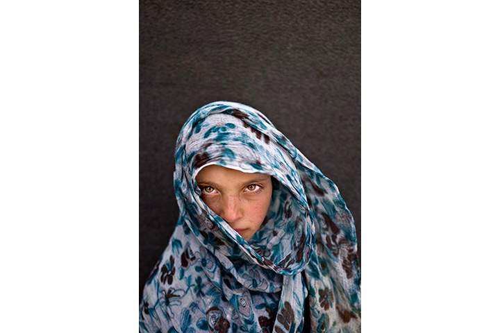 In this Sunday, March 13, 2016 photo, Syrian refugee girl Amna Zughayar, 9, from Deir el-Zour, Syria, poses for a picture at an informal tented settlement near the Syrian border on the outskirts of Mafraq, Jordan.