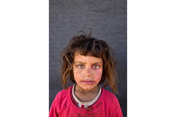 In this Friday, March 11, 2016 photo, Syrian refugee girl Mona Emad, 5, from Hassakeh, Syria, poses for a picture at an informal tented settlement near the Syrian border on the outskirts of Mafraq, Jordan.