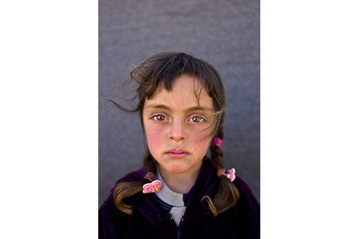 In this Friday, March 11, 2016 photo, Syrian refugee girl Zahra Mahmoud, 5, from Deir el-Zour, Syria, poses for a picture at an informal tented settlement near the Syrian border on the outskirts of Mafraq, Jordan.