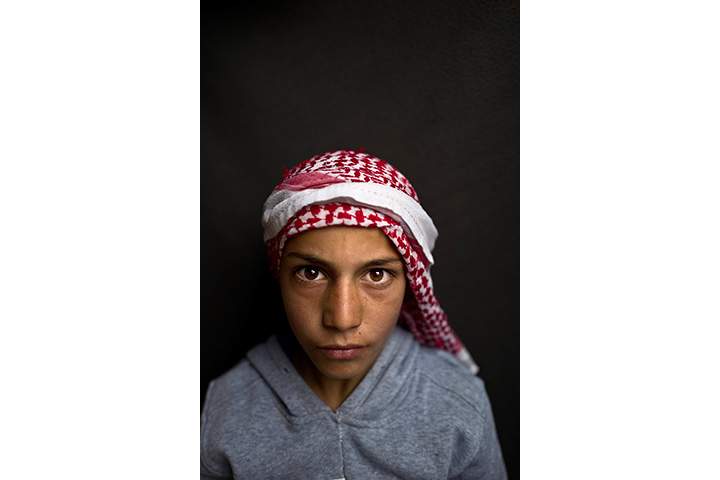 In this Sunday, March 13, 2016 photo, Syrian refugee boy Mohammed Bandar, 12, from Hama, Syria, poses for a picture at an informal tented settlement near the Syrian border on the outskirts of Mafraq, Jordan.