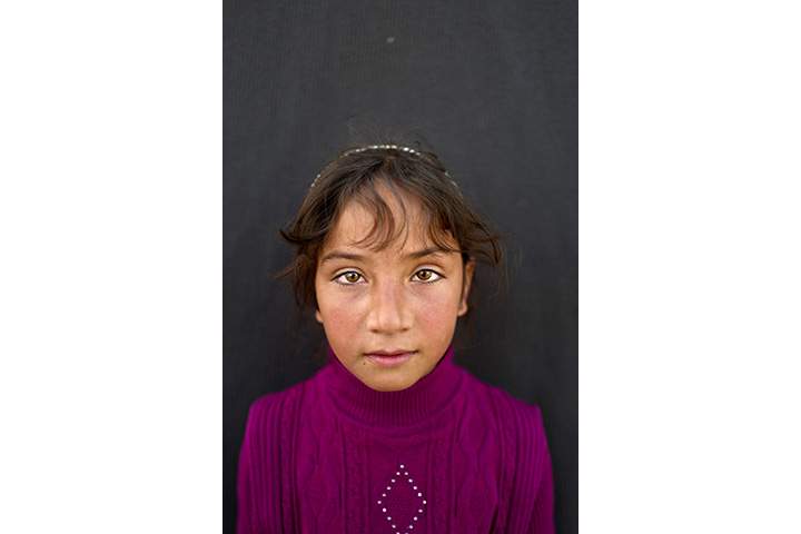 In this Saturday, March 12, 2016 photo, Syrian refugee girl Mariam Aloush, 8, from Homs, Syria, poses for a picture at an informal tented settlement near the Syrian border on the outskirts of Mafraq, Jordan.