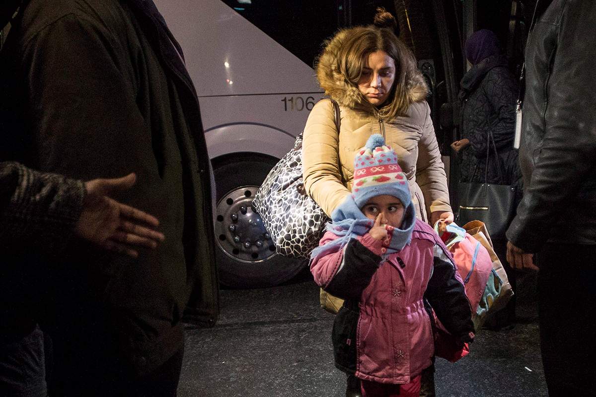 Syrian refugees step off a bus into a hotel after arriving on the first government-arranged flight into Toronto's Pearson Airport, on Friday, Dec. 11, 2015. 