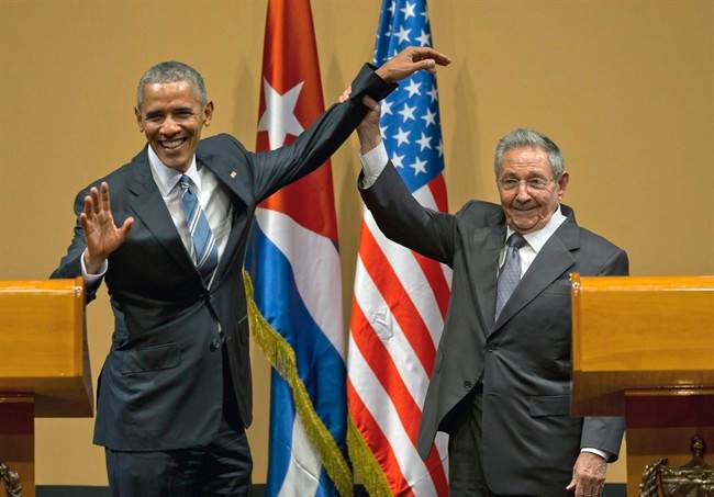 In this Monday, March 21, 2016 photo, Cuban President Raul Castro, right, lifts up the arm of President Barack Obama at the conclusion of their joint news conference at the Palace of the Revolution in Havana, Cuba.