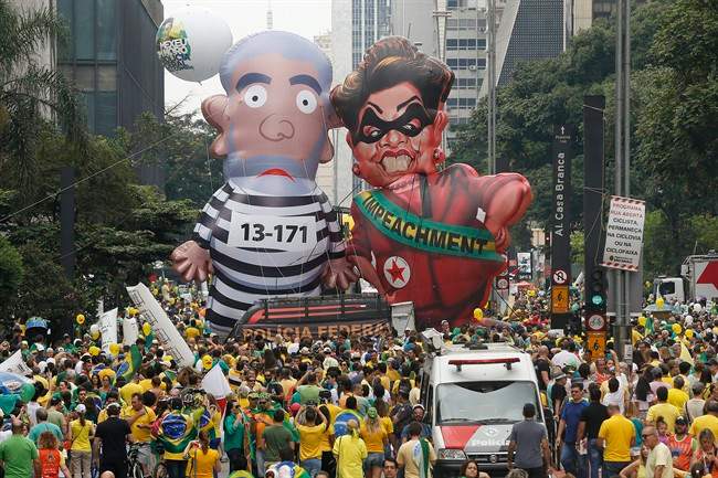 Demonstrators parade large inflatable dolls depicting Brazil's former President Luiz Inacio Lula da Silva in prison garb and current President Dilma Rousseff dressed as a thief.