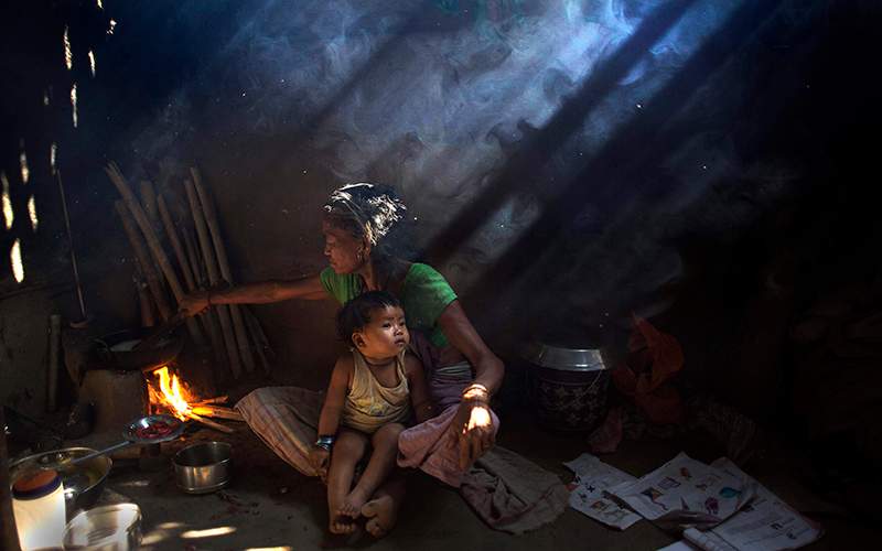 An elderly Indian woman cooks using firewood at her home at Gobhali village on the outskirts of Gauhati, India. 