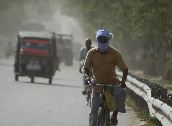 Indian commuters move on the side fringes of a busy road,  in a heavy dust strom and killer heat waves , during a hot day in Allahabad on April 12,2016. (Photo by Ritesh Shukla/NurPhoto via Getty Images).