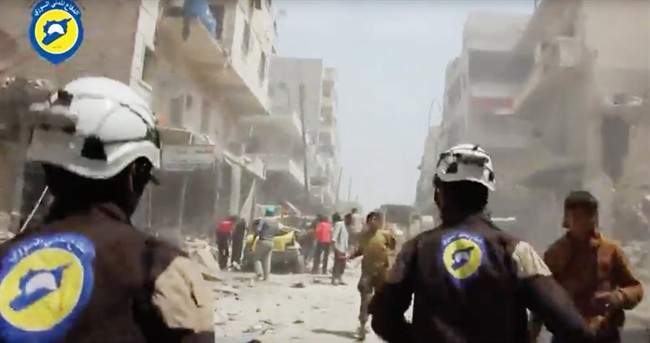 In this Sunday, April 24, 2016, file photo made from video posted online by the Syrian Civil Defense White Helmets, Civil Defense workers run after airstrikes and shelling hit Aleppo, Syria.