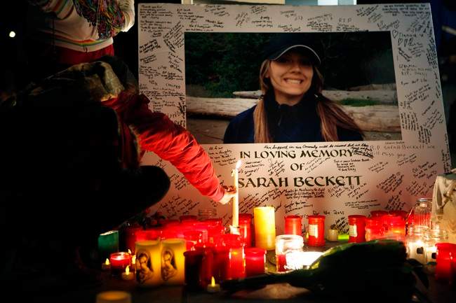 A supporter leaves a candle amongst others on a memorial during a candlelight vigil to remember West Shore RCMP Const. Sarah Beckett at Veteran's Memorial Park, in Langford, B.C., on Sunday, April 10, 2016.