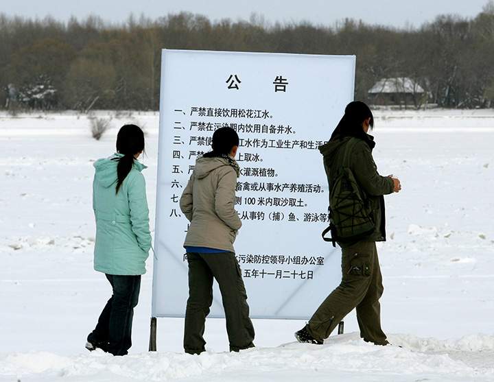Locals stop to read a sign warning about toxic pollution in the frozen Songhua River, on the bank of the river in Jiamusi, in China's northeast Heilongjiang province Monday Dec. 5, 2005.   