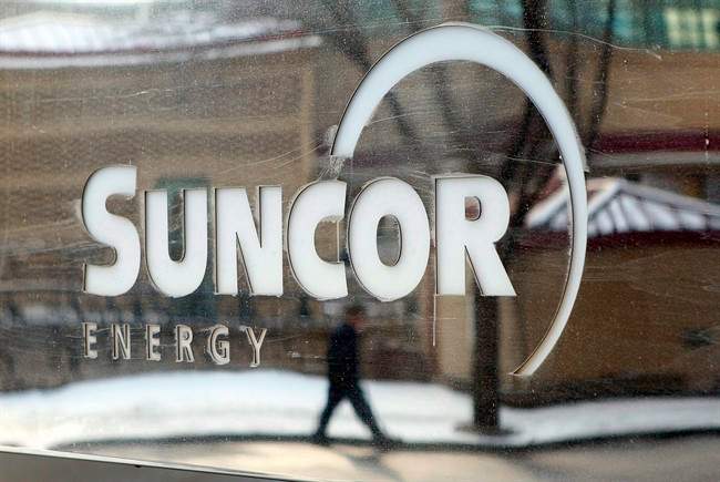 A pedestrian is reflected in a Suncor Energy sign in Calgary, Monday, Feb. 1, 2010.