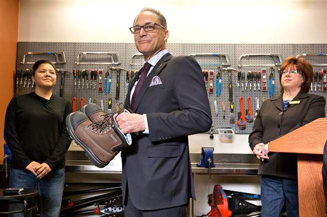 Alberta Finance MinisterJoe Ceci prepares to donate work boots to Women Building Futures student Kim Brertton, left, as CEO of Women Building Futures JudyLynn Archer looks on during a pre-budget photo opportunity in Edmonton, on Monday April 13, 2016. 
