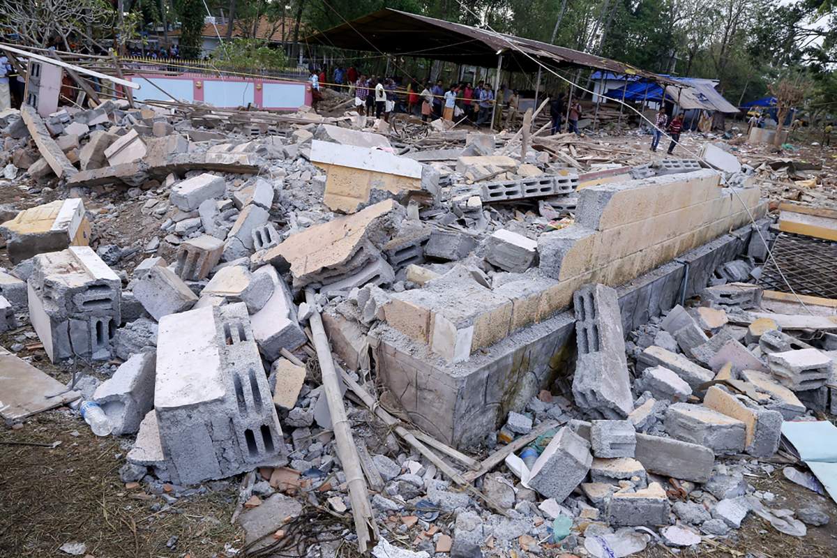 Indian officials and bystanders gather beside a collapsed building after an explosion and fire at The Puttingal Devi Temple in Paravur early April 10, 2016.