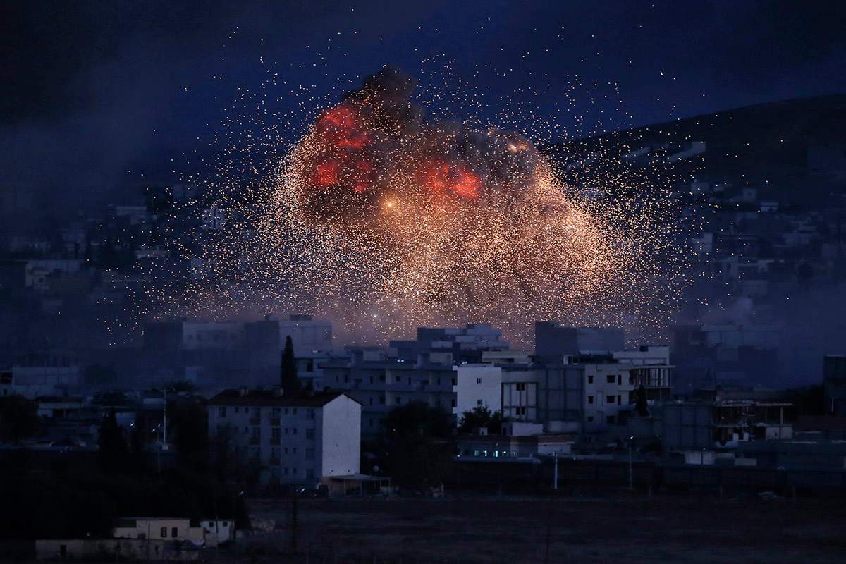 In this Oct. 20, 2014 file photo, thick smoke and flames erupt from an airstrike by the U.S.-led coalition in Kobani, Syria, as seen from a hilltop on the outskirts of Suruc, at the Turkey-Syria border. 