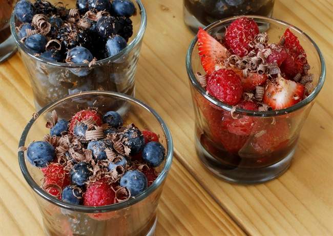 Fresh berries served with a sugar syrup spiked with cocktail bitters and garnished with shavings of dark chocolate .