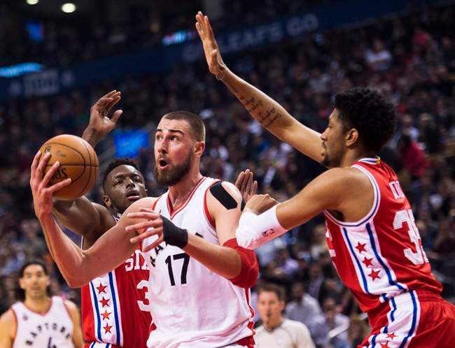 Toronto Raptors centre Jonas Valanciunas (17) moves the ball past Philadelphia 76ers forward Christian Wood (35) and 76ers forward Robert Covington (33) during first half NBA basketball action in Toronto on Tuesday, April 12, 2016. THE CANADIAN PRESS/Nathan Denette.