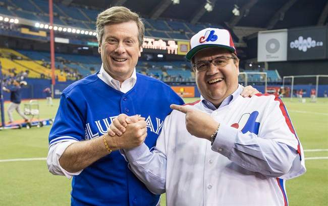 Montreal Mayor Denis Coderre, right, shares a laugh with Toronto counterpart John Tory prior to the Blue Jays facing the Boston Red Sox in a spring training baseball game in Montreal.