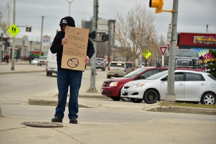 An officer stands by the road holding a sign in while another tickets those too distracted to read it because they're on their phone. 