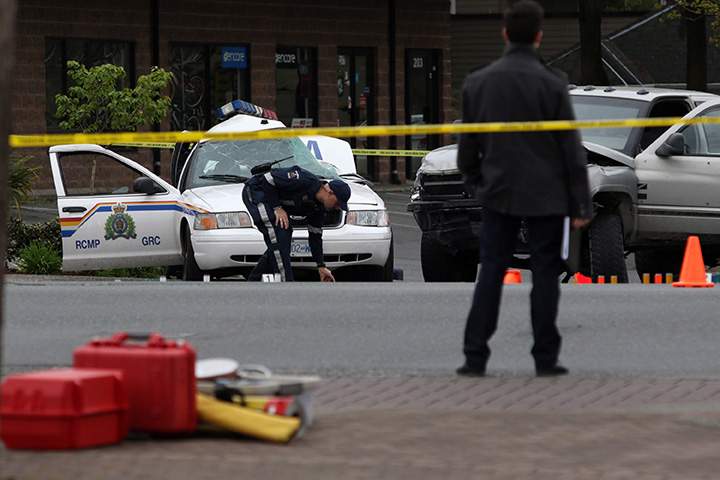 A Saanich police officer examines the scene of the crash involving a police car and a pickup truck in Langford, B.C., Tuesday, April 5, 2016. RCMP Const. Sarah Beckett was killed in the crash. 
