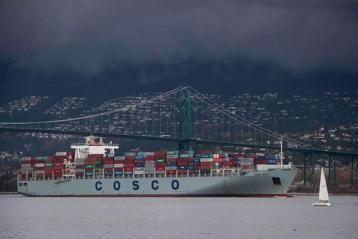 A sailboat leaves the harbour as the container ship Cosco Pacific, arriving from Prince Rupert, passes under the Lions Gate Bridge to dock at port in Vancouver, B.C., on Thursday November 6, 2014. 
