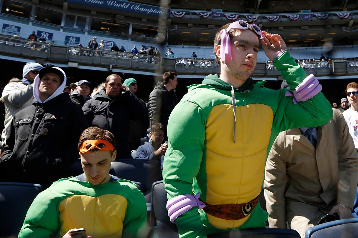 Joe Spillo, left, looks at his cell phone while John Welch, both of Yorktown Heights, N.Y., looks around from their pricey Legends Suites luxury seats behind home plate before an opening day baseball game between the New York Yankees and the Houston Astros in New York, Tuesday, April 5, 2016. 