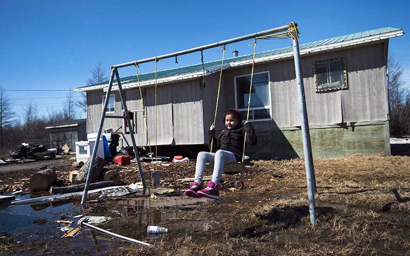 Eight-year-old Shakira Koostachin plays on a swing in the northern Ontario First Nations reserve in Attawapiskat, Ont.