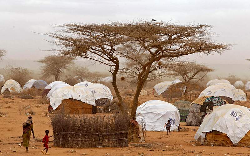 Refugees walk amongst huts at a refugee camp in Dadaab, Kenya. Kenya's interior minister said Wednesday, May 11, 2016 that the government will close Dadaab refugee camp which has hundreds of thousands of Somali refugees and is often referred to as the world's largest refugee camp. 