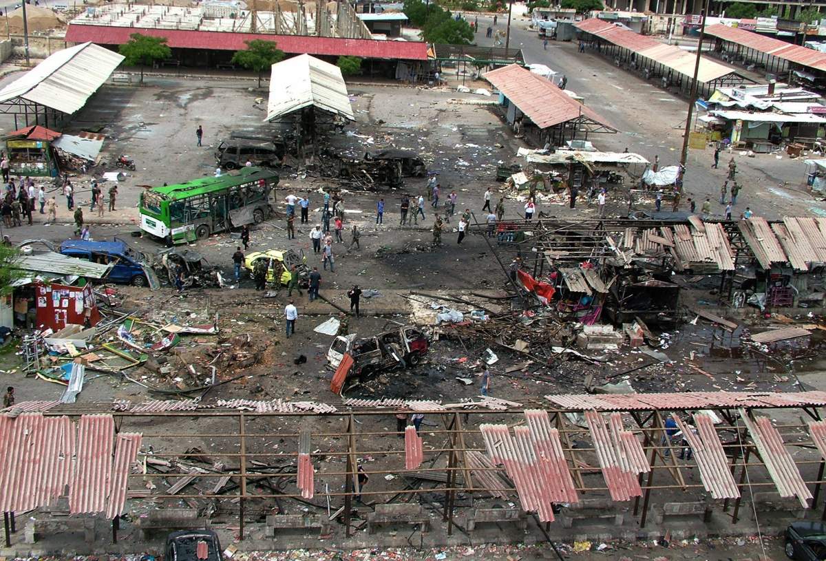 In this photo released by the Syrian official news agency SANA, Syrians gather around damages after a bombing attack at a bus station, in the coastal town of Tartus, Syria, Monday, May 23, 2016. A series of rare explosions including suicide bombings rocked coastal government strongholds in Syria Monday, killing more than 70 people and wounding dozens more, state media and opposition activists said. The Islamic State group claimed responsibility for the attacks. 