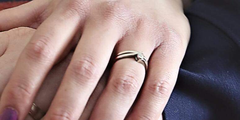 The engagement ring has a single diamond set on top, with a slight twist in the ring near the  stone.