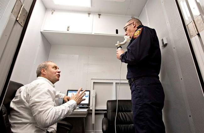 Dr. Jeremy Beach, left, tests the lung function of firefighter captain Kelly Lehr with a spirometer at a fire hall in Sherwood Park, Alta., on Wednesday, May 18, 2016. University of Alberta researcher Nicola Cherry set up a mobile lab to test firefighters for breathing problems after returning from Fort McMurray.