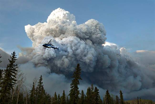 A helicopter flies past a wildfire in Fort McMurray, Alta., on Wednesday May 4, 2016. 