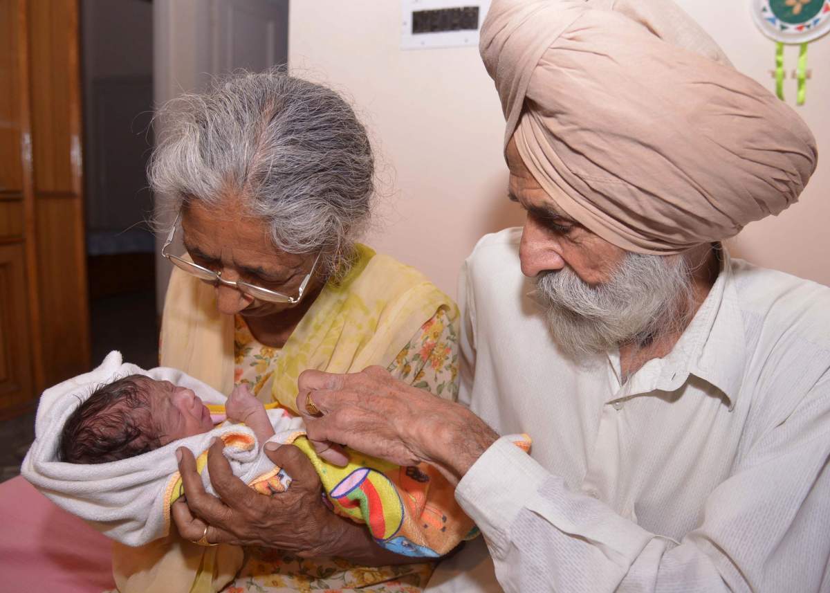 Indian parents Mohinder Singh Gill (R), 79, and Daljinder Kaur, 70, pose for a photograph as they hold their newborn baby boy Arman at their home in Amritsar on May 11, 2016.
