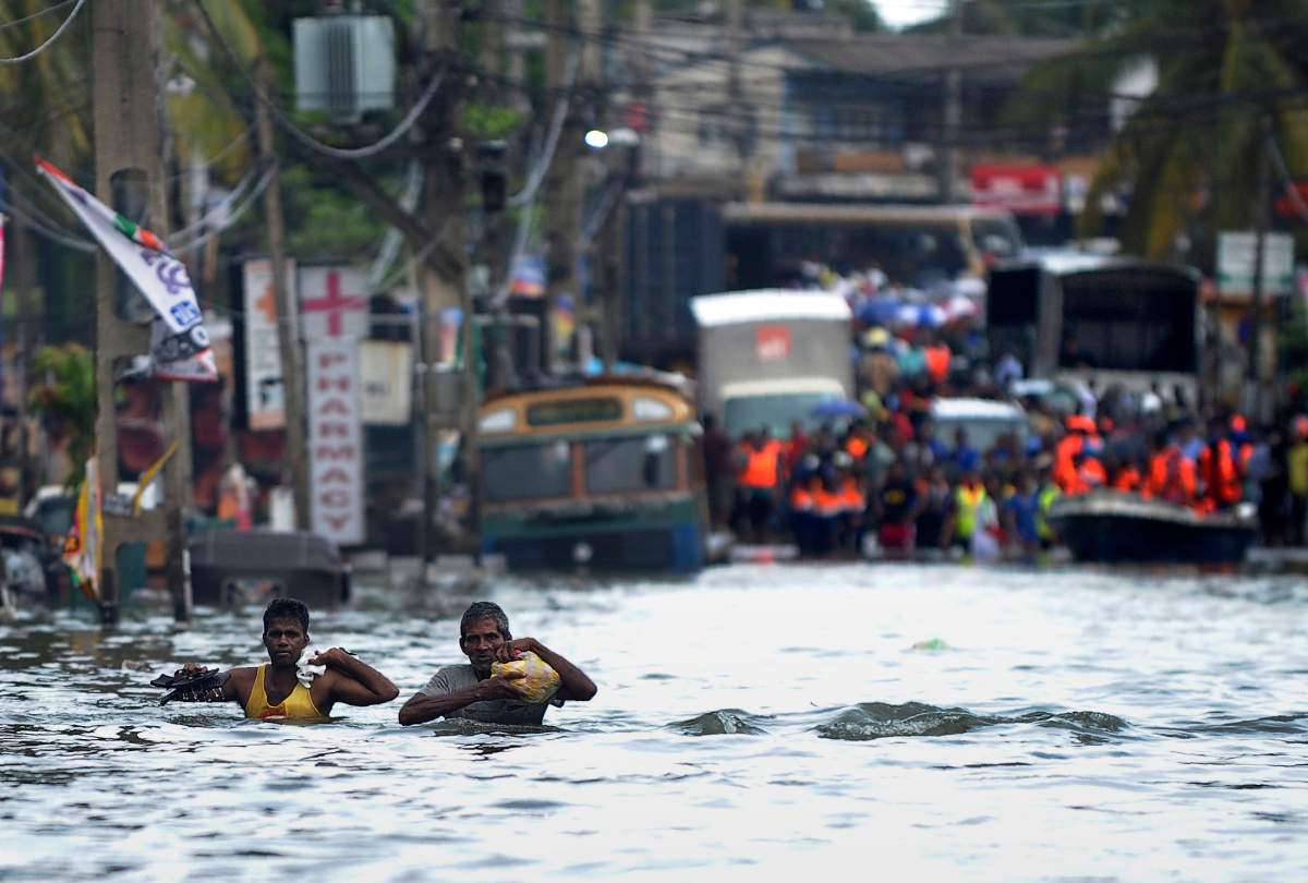 Sri Lankan residents wade through floodwaters in the Kolonnawa suburb of Colombo on May 20, 2016.  
Desperate Sri Lankans clambered onto rubber dinghies and makeshift rafts May 20 to flee their homes in the flooded capital Colombo as fresh downpours elsewhere stalled rescue efforts at disaster zones. The heaviest rains in a quarter of a century have pounded the island since last weekend, sparking huge landslides that have buried victims in up to 15 metres of mud. 