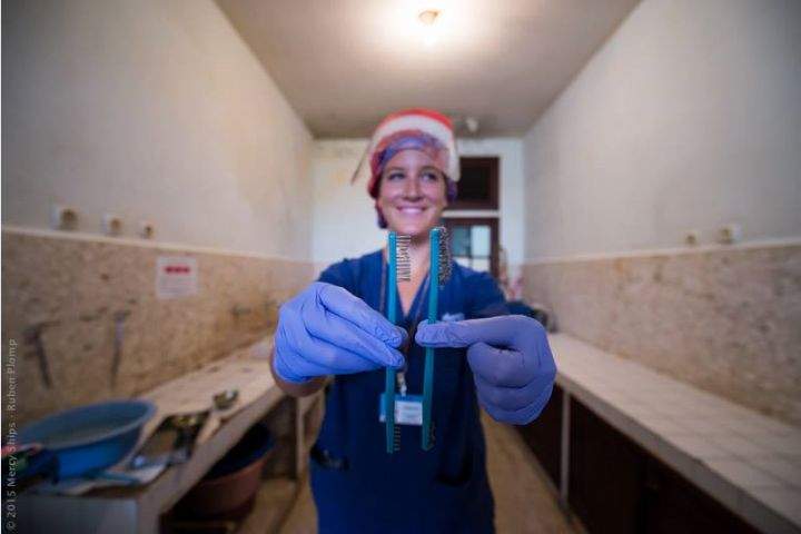 Christina Fast of SPECT holds up worn brushes while teaching in Madagascar.
