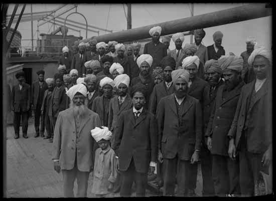 Sikh men and a boy are pictured onboard the Komagata Maru. Businessman Gurdit Singh is seen wearing a light-coloured suit in the left foreground.