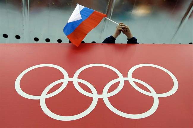 A Russian skating fan holds the country's national flag over the Olympic rings.