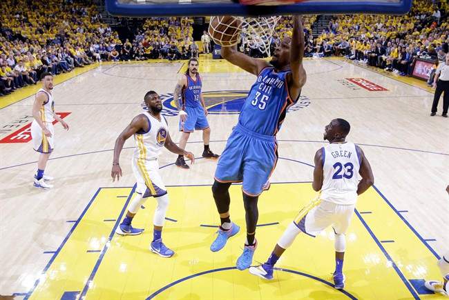 Oklahoma City Thunder's Kevin Durant (35) dunks past Golden State Warriors' Draymond Green (23) and Festus Ezeli (31) during the first half in Game 2 of the NBA basketball Western Conference finals Wednesday, May 18, 2016, in Oakland, Calif.