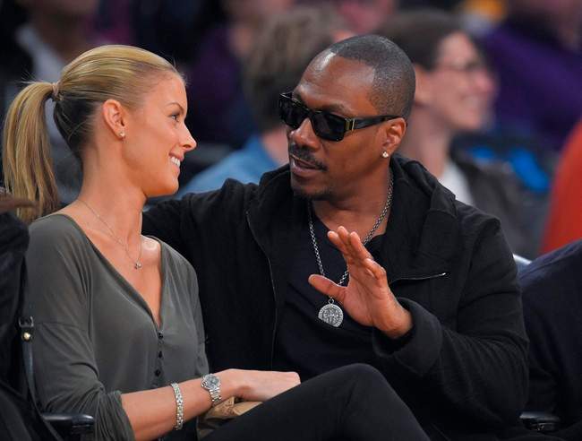 FILE - In this April 12, 2015, file photo, actor Eddie Murphy talks with his girlfriend Paige Butcher during an NBA basketball game between the Los Angeles Lakers and the Dallas Mavericks. 
