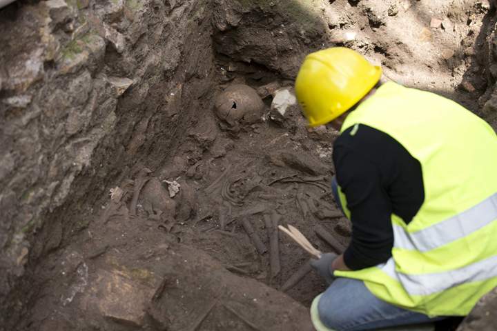 An archaeologist checks human bones as ancient Roman ruins of former barracks were discovered during work on a new underground line in Rome, Monday, May 16, 2016.