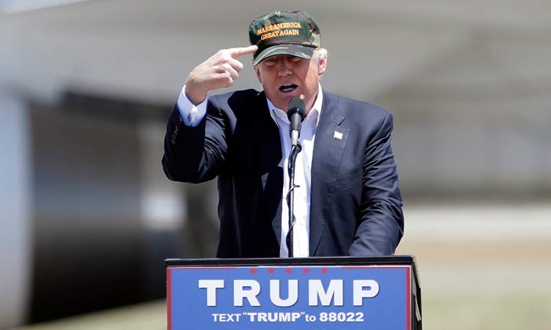 Republican presidential candidate Donald Trump gestures to a his camouflaged "Make America Great" hat as he discuses his support by the National Rifle Association at a campaign rally at the Redding Municipal Airport Friday, June 3, 2016, in Redding, Calif. 