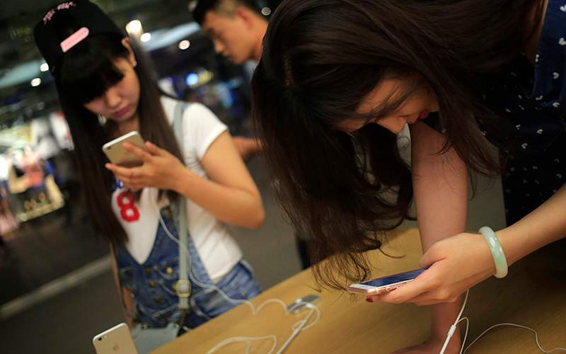 Customers looking at iPhone 6 and iPhone 6 Plus mobile phones in an Apple Store in Beijing, China, 17 June 2016. 