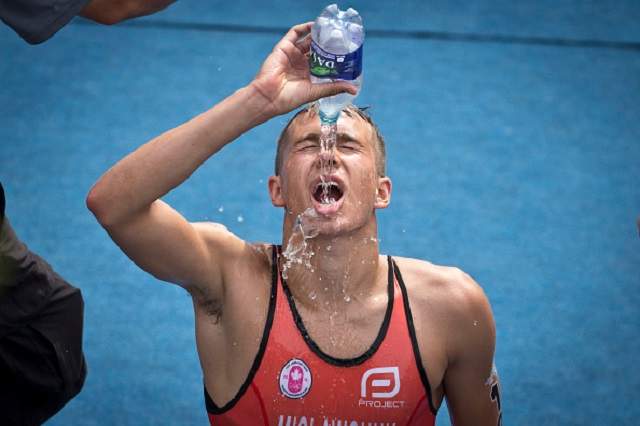 Tyler Mislawchuk douses himself with water after kneeling down at the finish line. He finished 10th in the 2015 Pan Am games triathlon on the shore of Lake Ontario in Toronto Sunday morning.