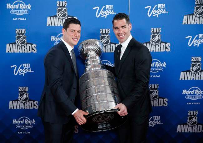Pittsburgh Penguins' Sidney Crosby, left, and Pascal Dupuis hold up the Stanley Cup on the red carpet before the NHL Awards show, Wednesday, June 22, 2016, in Las Vegas.
