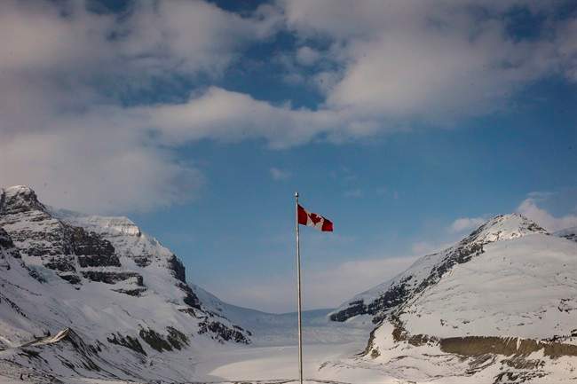 FILE - The Canadian flag flies over the Columbia Icefields' Athabasca Glacier in Jasper National Park, in a May 7, 2014, file photo. Parks Canada is preparing to go to the public with plans for a $66-million, 107-kilometre bike trail from Jasper, Alta., to the Columbia Icefields along the Jasper-Banff highway, one of the country's most scenic drives.
