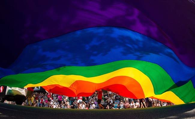 A large rainbow flag is carried down Robson Street during the Vancouver Pride Parade in Vancouver, B.C., on Sunday, August 2, 2015.